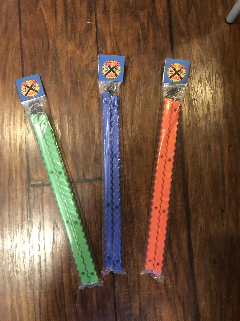 Green, blue and orange Riff Raff Zig Zag rail packages on a wood floor; each selected color is sold as one pair