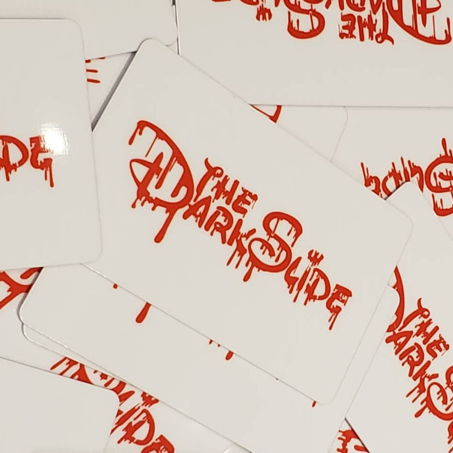 A closeup pile of white gift cards featuring the words 'THE DARK SLIDE' printed in a red stylized font.