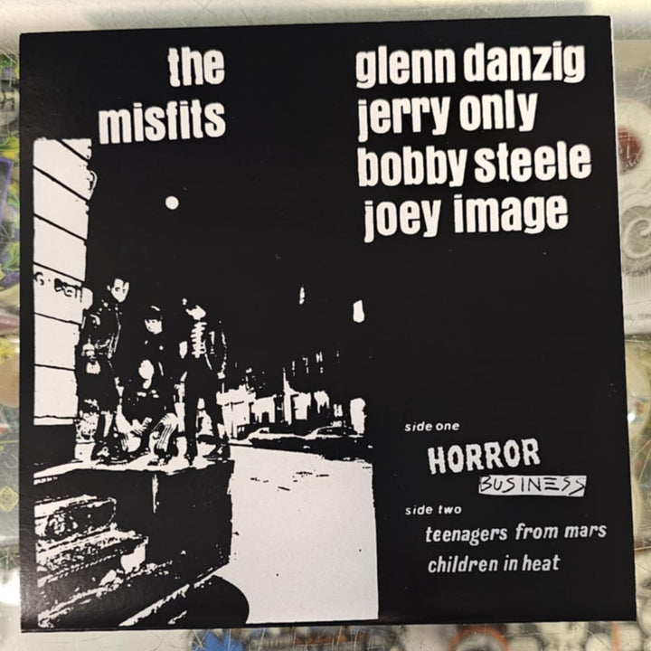 Vinyl record cover with text and black and white image of people in a room, on a store shelf.