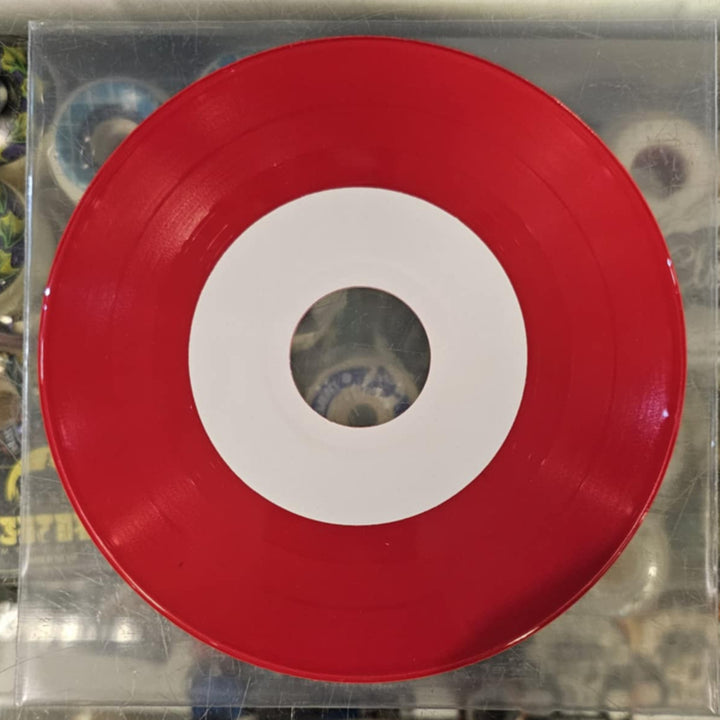 Red vinyl record with white center on a clear plastic sleeve against a colorful background.
