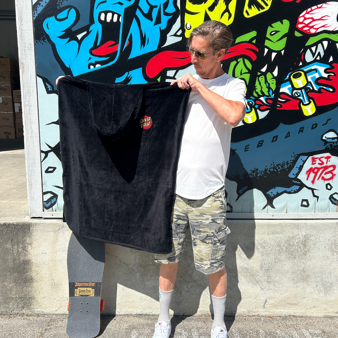 Man holding a black towel in front of a colorful mural
