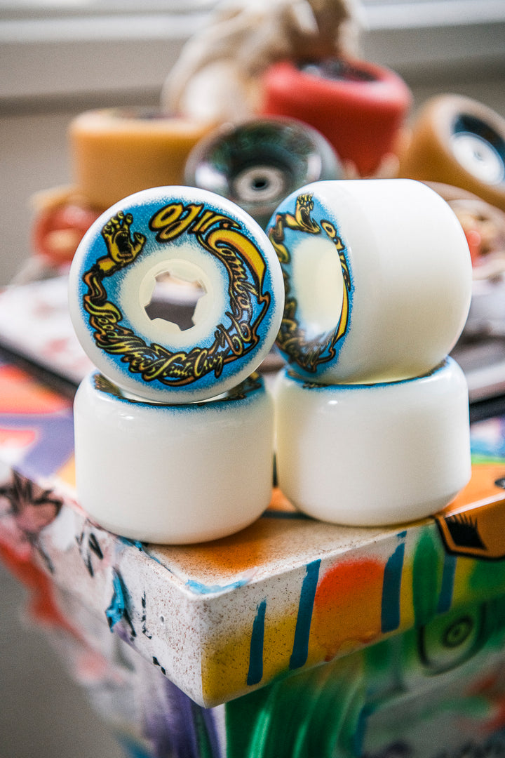 Close-up of two skateboard wheels with decorative hub design on a colorful surface.