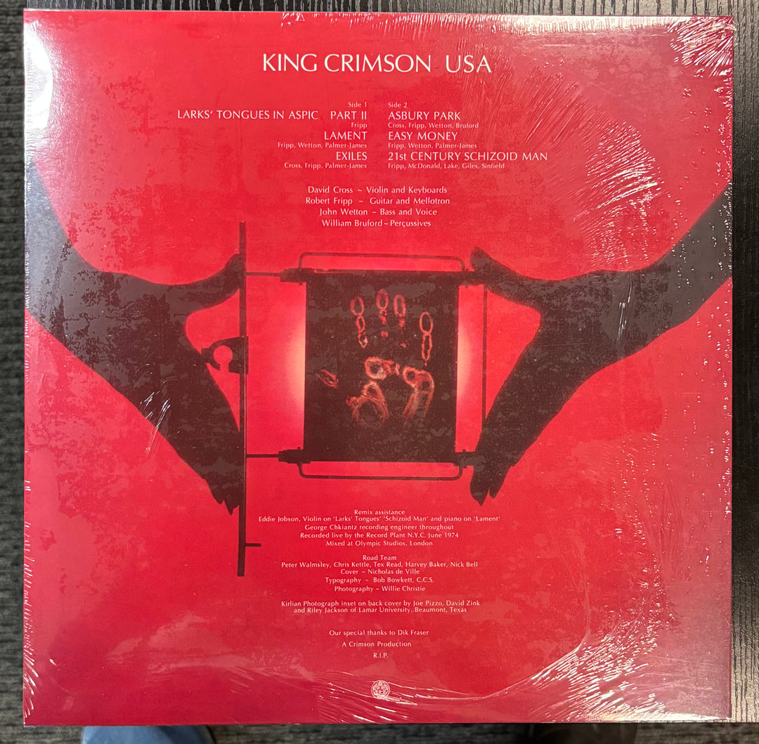 KING CRIMSON – USA record cover with red background and black silhouette of a person holding an album, featuring King Crimson USA text.