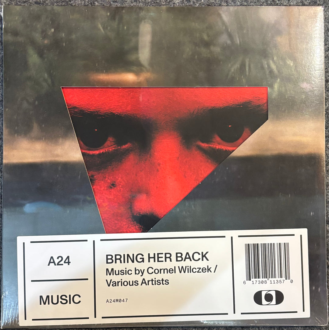 Vinyl record sleeve for Cornel Wilczek's 'Bring Her Back' release, featuring a triangular red cutout of a face over a dark, moody background, with a white barcode label at the bottom.