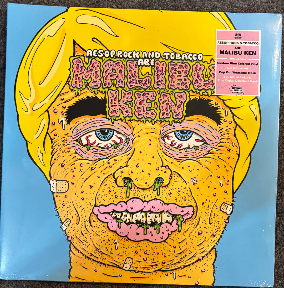 A vinyl record sleeve for Aesop Rock and Tobacco's 'Malibu Ken' LP, featuring a highly detailed, surreal cartoon illustration of a face with yellow hair and skin, pink lips, and bandages, set against a light blue background. A pink sticker on the top right indicates the release details.