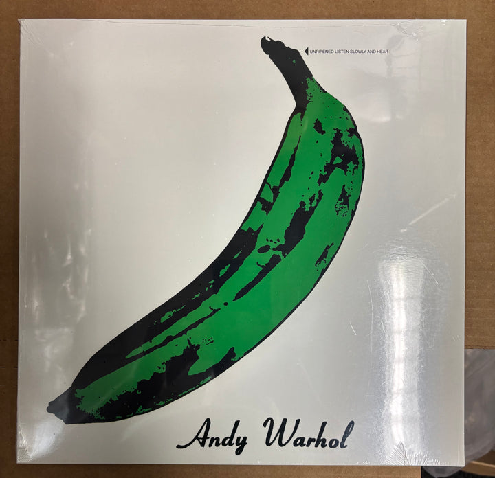 Green banana with black stripes on a white background, featuring Andy Warhol's name.