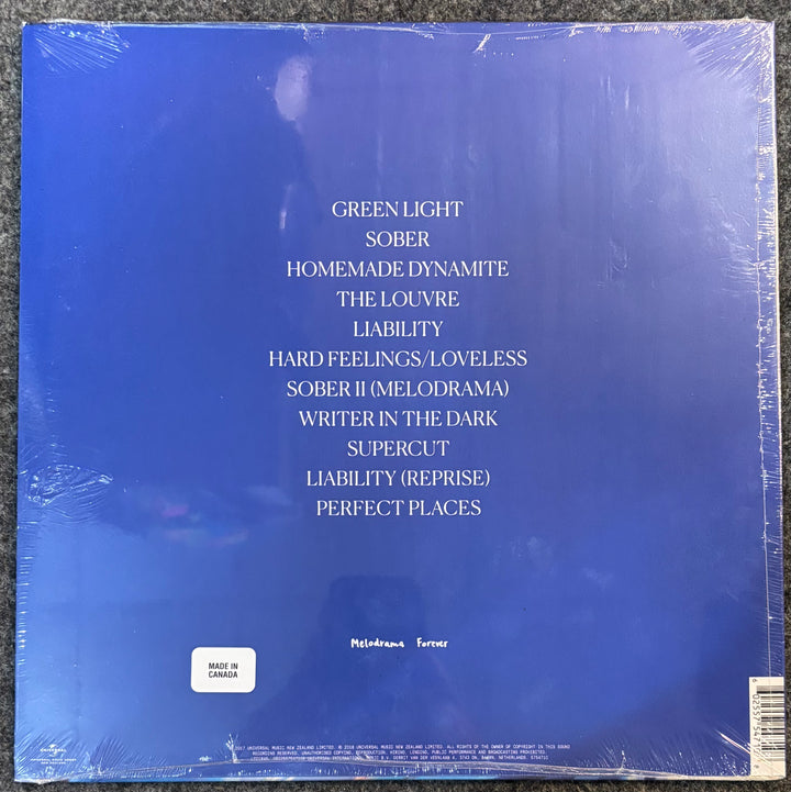 The back cover of Lorde - Melodrama, sealed in plastic shrink wrap, showing the tracklist in white text on a blue background.