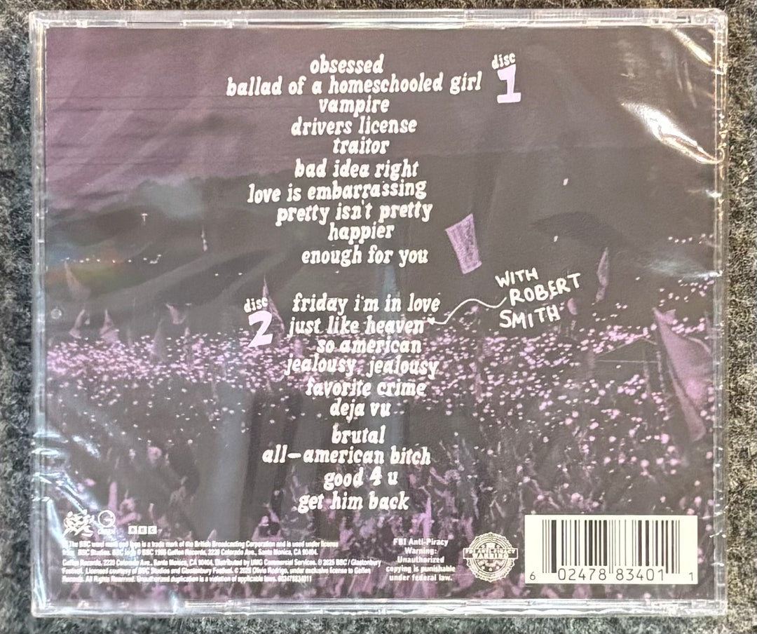 Back cover of OLIVIA RODRIGO – LIVE FROM GLASTONBURY CD with text and a barcode on a textured surface