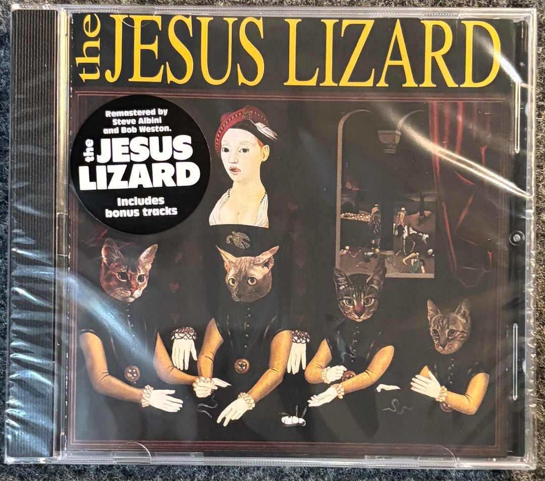 The Jesus Lizard album CD in a clear jewel case, wrapped in protective plastic. The cover art features a dark, surreal scene with a woman's bust, several cat-headed figures in black clothing, and large yellow text reading 'the JESUS LIZARD' at the top.