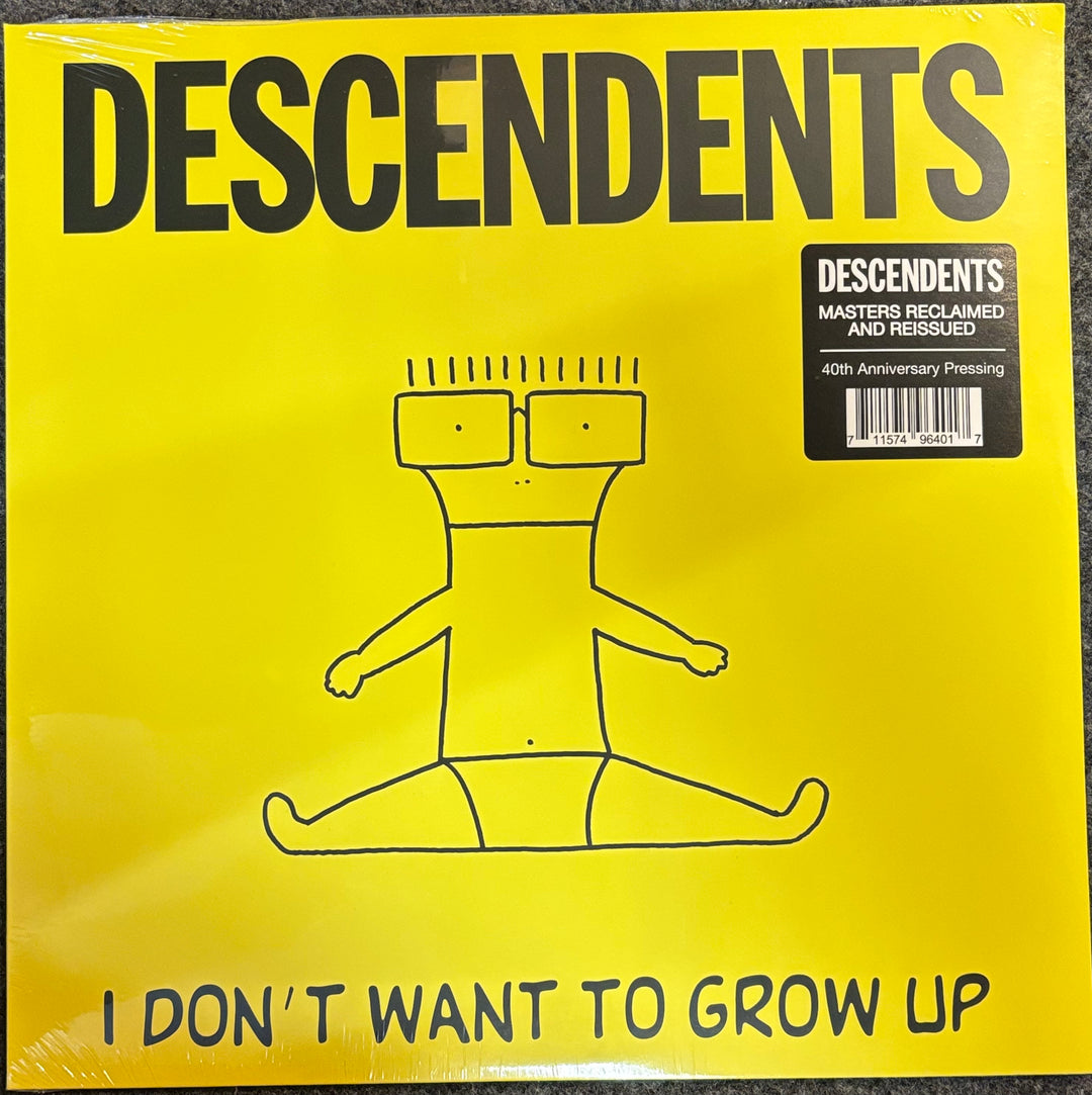 A bright yellow Descendents vinyl record cover for 'I Don't Want to Grow Up', featuring a simple black line drawing of a seated figure and a black sticker in the top right corner.