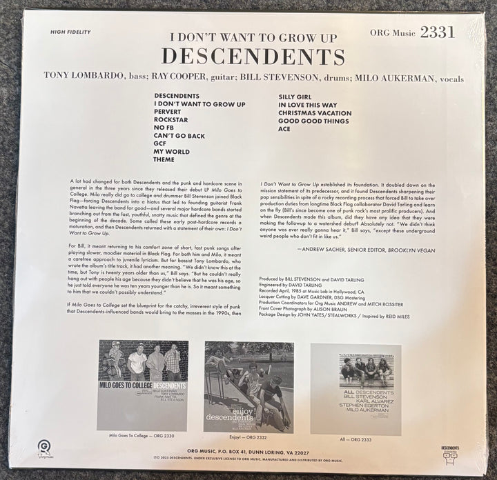 The back cover of a vinyl record sleeve for Descendents' album 'I Don't Want to Grow Up', photographed flat against a dark textured background. The cover is off-white with black text and small black-and-white photos.