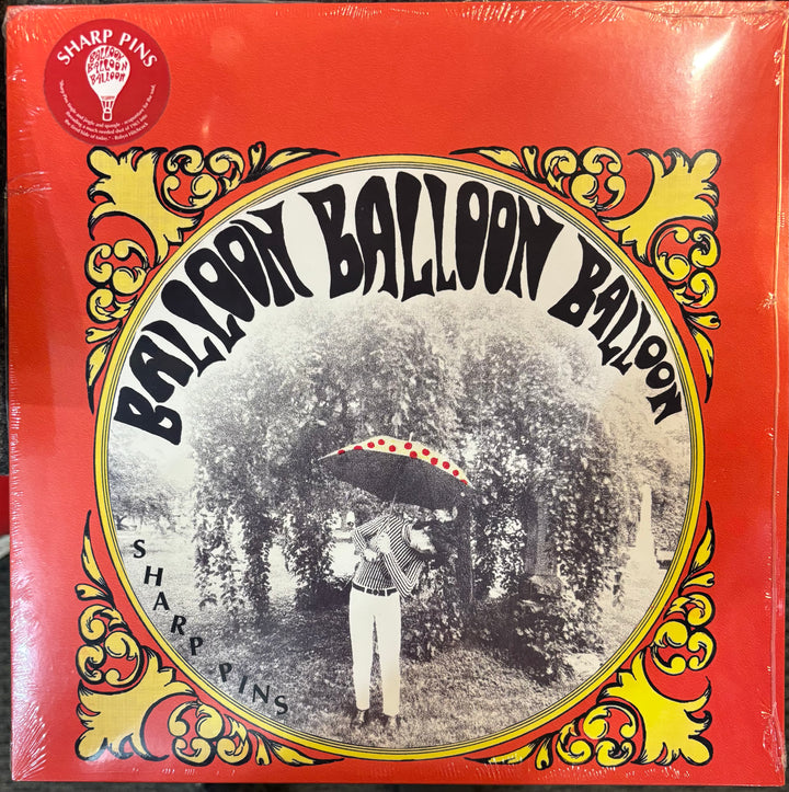 A vinyl record cover for Sharp Pins ‎– Balloon Balloon Balloon, featuring a bright red background with yellow and gold ornate scrollwork and a central circular black-and-white photograph of a person holding a red-and-white balloon.