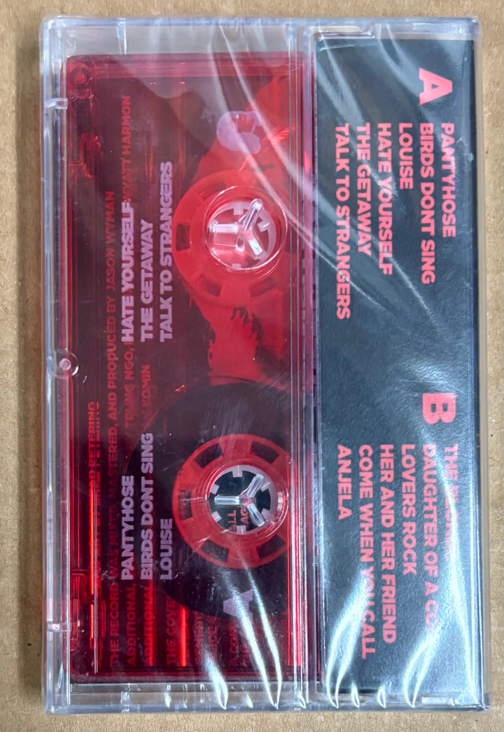 Cassette tape with red label and clear casing on a beige background