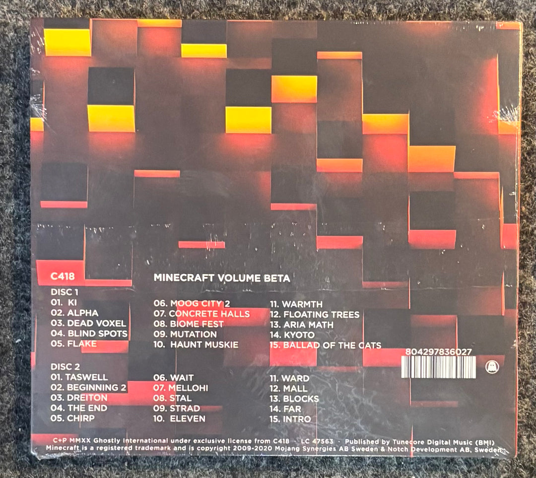 The back cover of a Minecraft Volume Beta CD case, featuring a dark brown and black geometric block pattern with red and yellow highlights. The tracklist is printed in white and red text, and the Minecraft logo is visible at the bottom.
