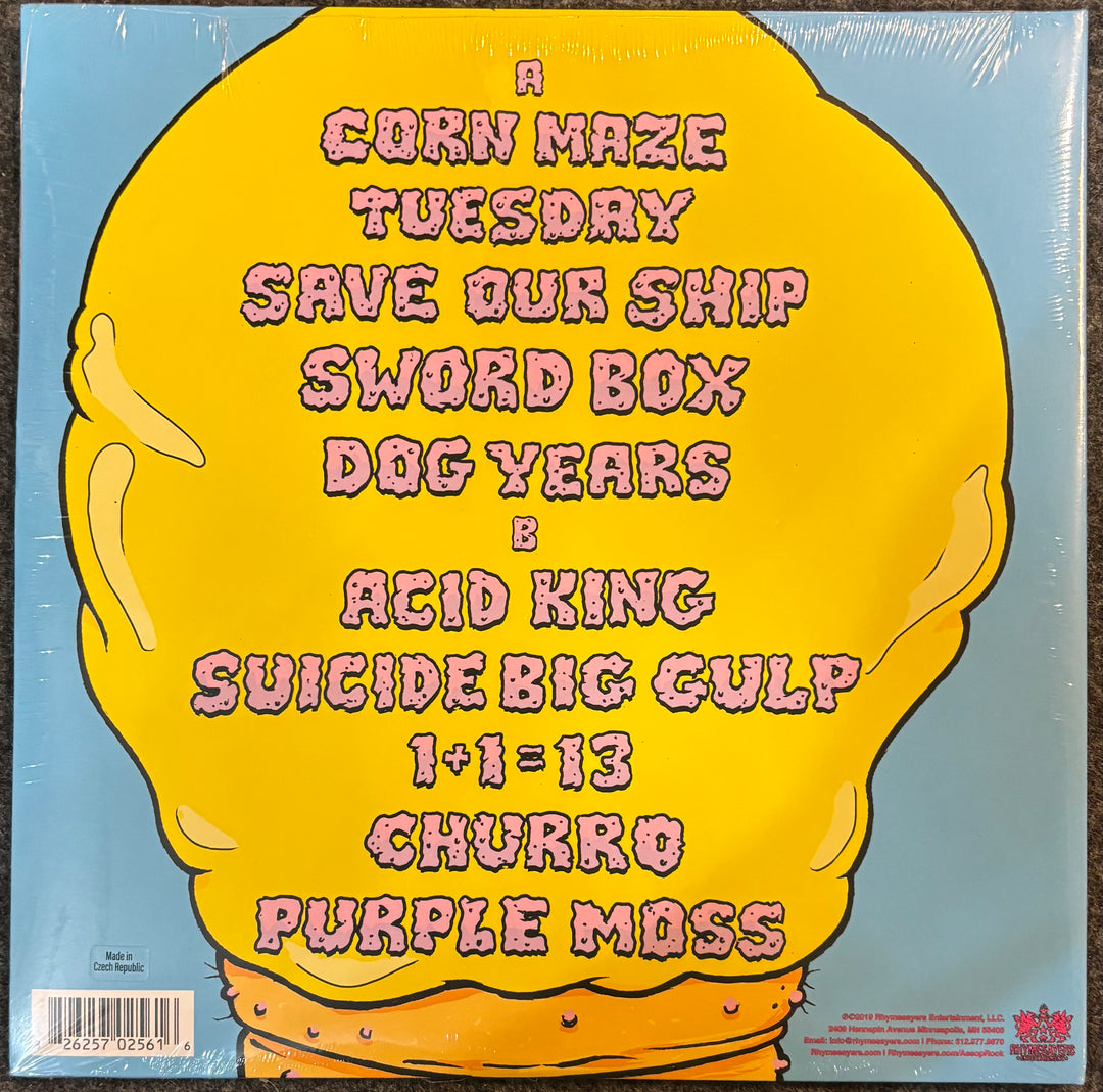 The back cover of Aesop Rock & TOBACCO - Malibu Ken, featuring a large yellow cartoon character on a light blue background with pink text listing the band members and track names.
