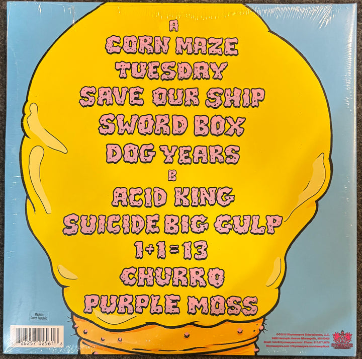 The back cover of Aesop Rock & TOBACCO - Malibu Ken, featuring a large yellow cartoon character on a light blue background with pink text listing the band members and track names.