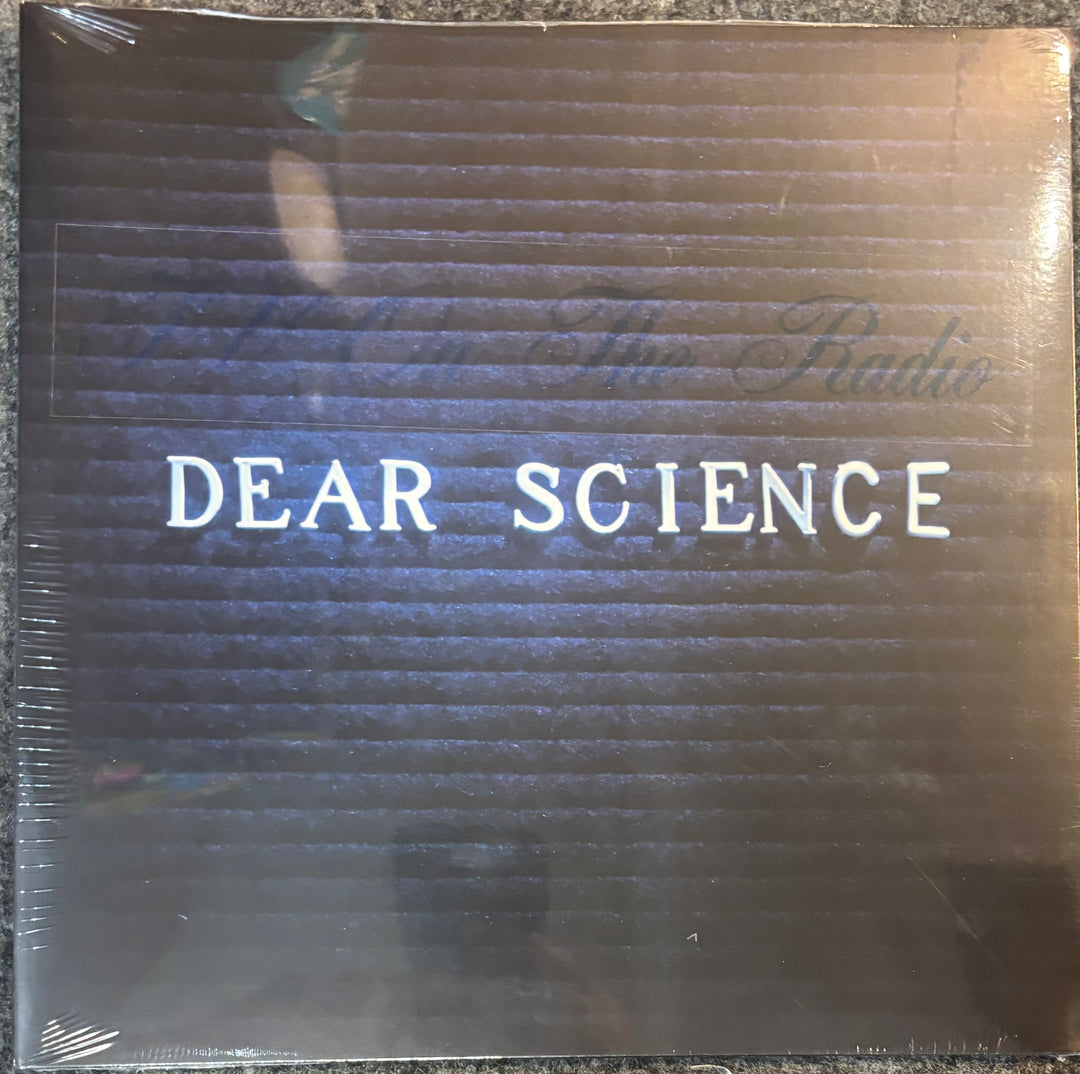 A sealed vinyl record sleeve for TV On The Radio - Dear Science', featuring a dark brown textured background with horizontal lines and light blue text.
