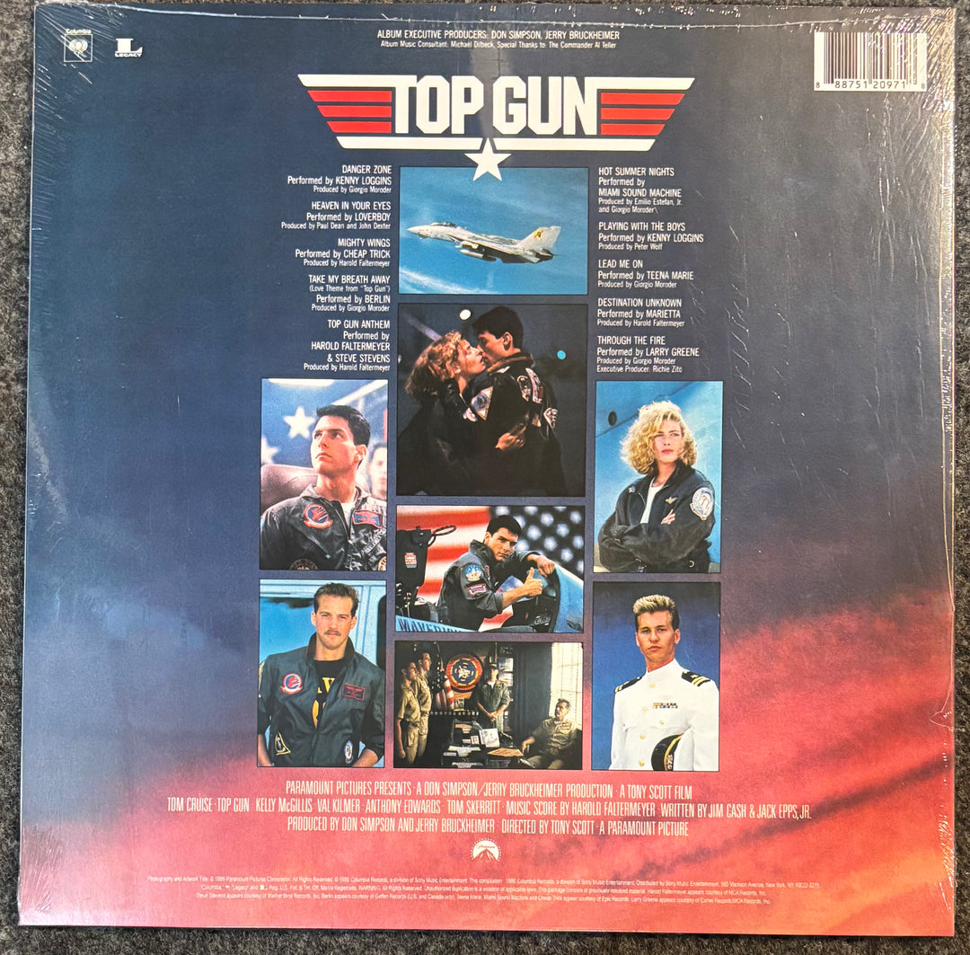 The back cover of the Top Gun soundtrack vinyl record, sealed in its plastic shrink wrap, showing the film's cast and production credits on a dark blue and red gradient background.