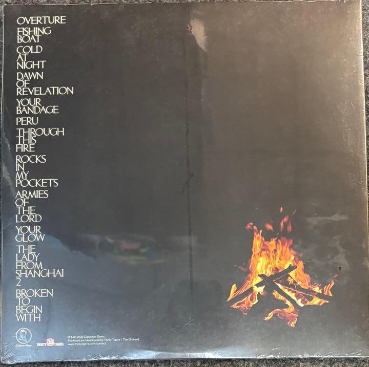 Vinyl record sleeve cover for the band Mountain Goats - Through This Fire Across From Peter Balkan, featuring a dark black background with the album's tracklist printed vertically on the left in white text and a small campfire graphic in the bottom right corner.