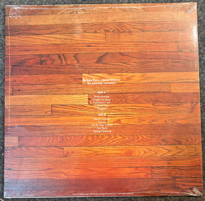 Bright Eyes/Neva Dinova - One Jug of Wine, Two Vessels record with wooden panel design and text on a dark surface