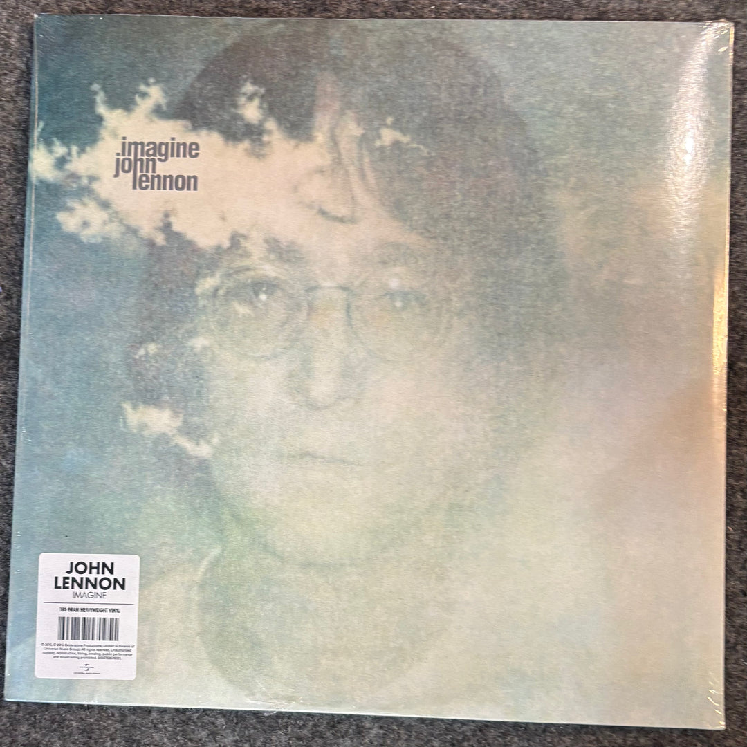 John Lennon 'Imagine' vinyl record album cover, sealed in plastic with a barcode sticker in the lower left, photographed on a dark textured surface.
