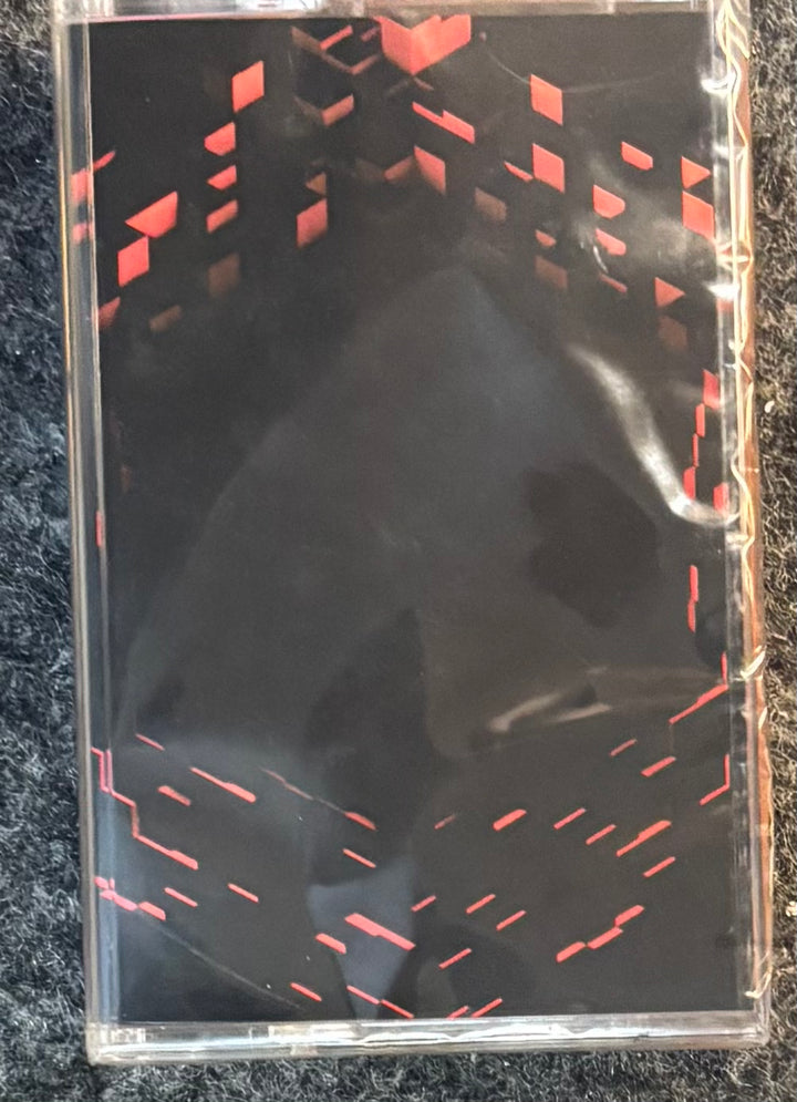 C418 - Minecraft Volume Beta cassette-style case or sleeve with red geometric dash patterns, photographed on a dark textured surface.