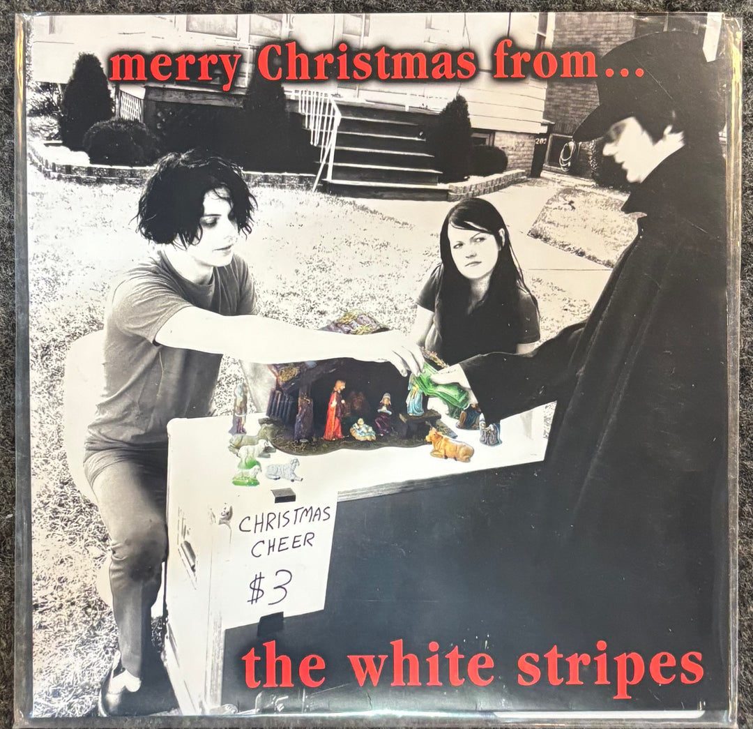 Album cover for WHITE STRIPES, THE - MERRY CHRISTMAS FROM... with black and white photo of three people around a table with Christmas decorations.