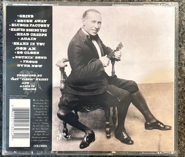 ALICE IN CHAINS – ALICE IN CHAINS (3 LEGGED DOG) CD cover with a black and white photo of a man sitting on a chair holding a guitar, with text on the left side.