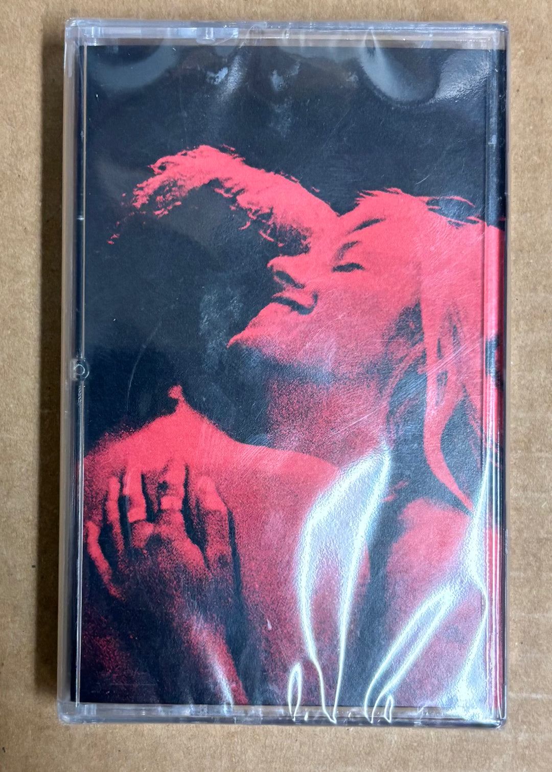 Cassette tape with a red and black graphic design on a beige background