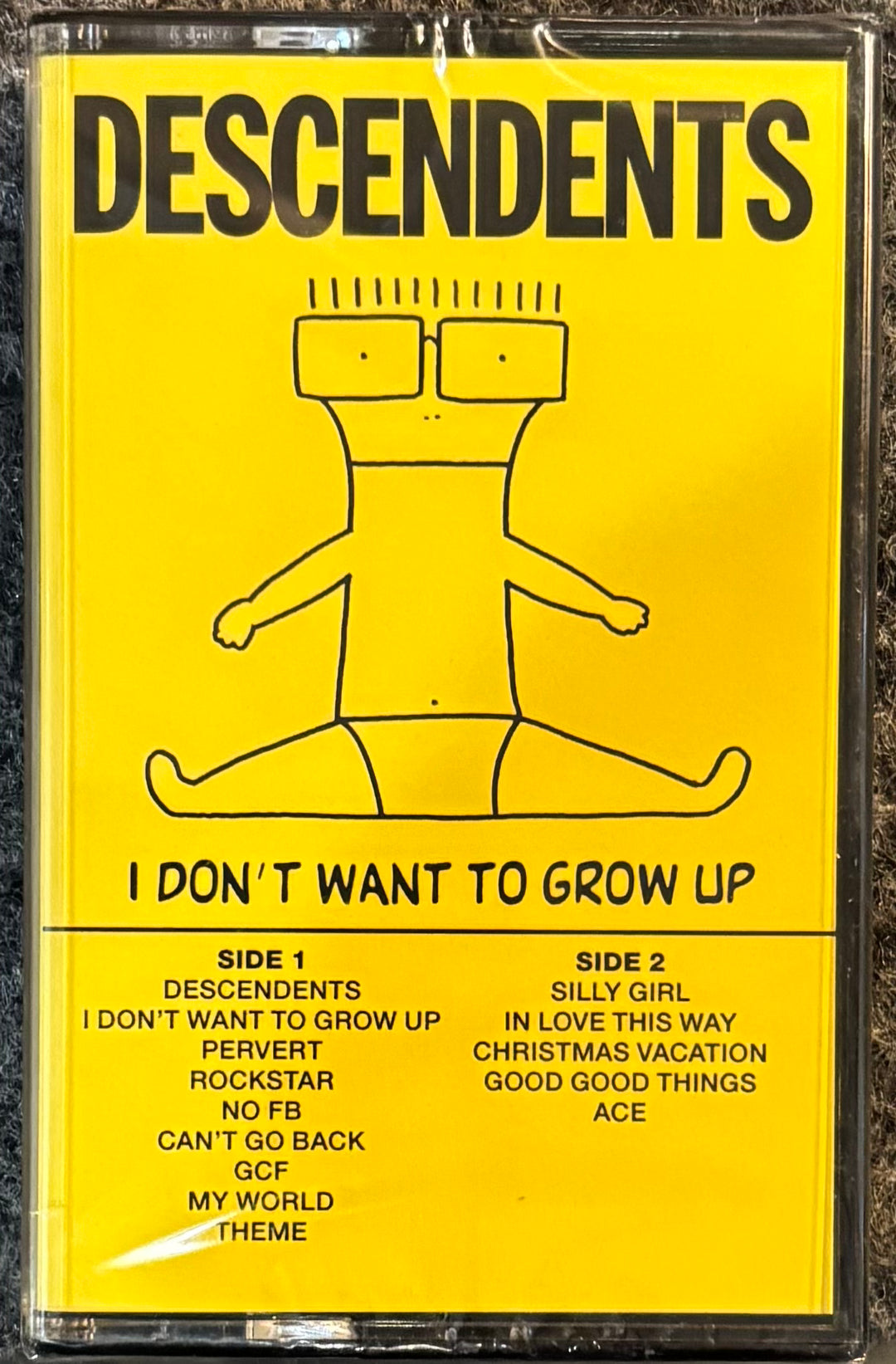 Cassette tape with 'Descendents' album cover featuring a yellow background and black text.