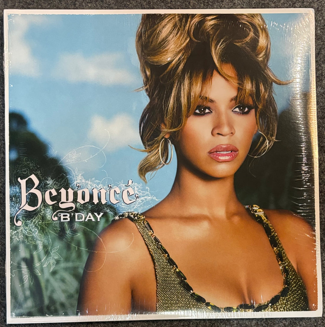 Beyonce '8' Day' vinyl record cover, sealed in plastic shrink wrap, displayed on a dark textured surface.