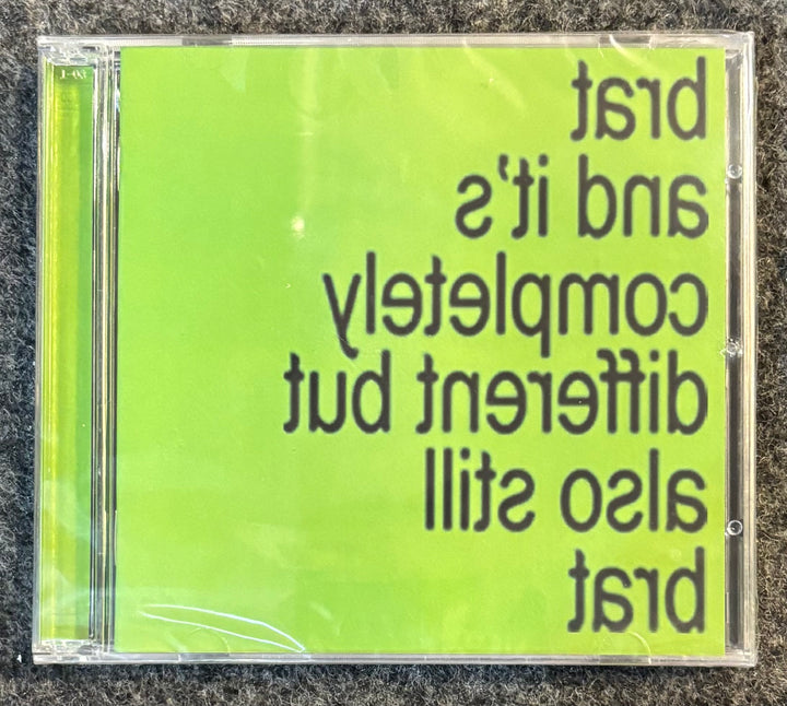 Charli XCX – Brat And It's Completely Different But Also Still Brat CD case with green cover and text on a textured surface