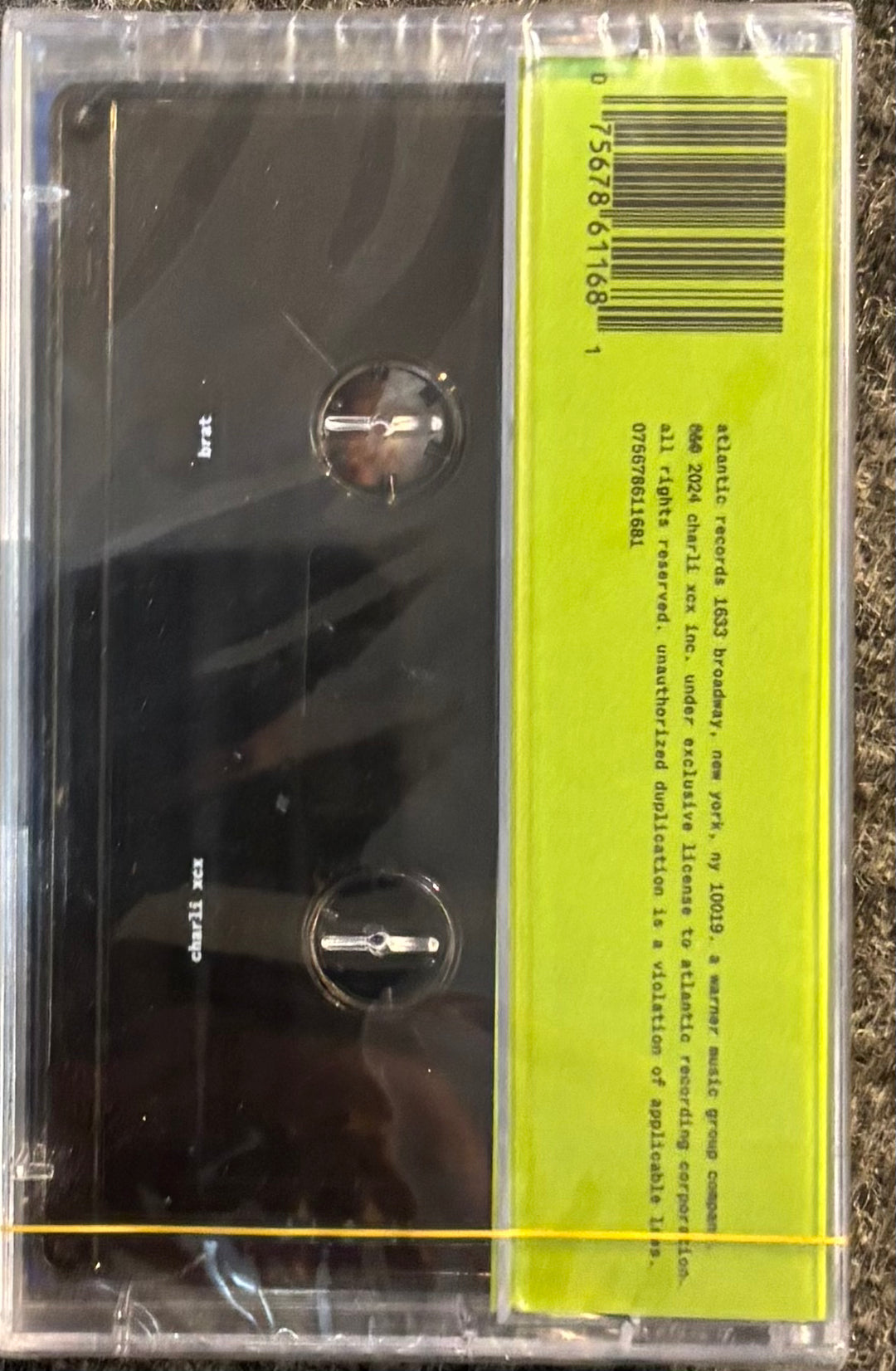 CHARLIE XCX - BRAT tape with a yellow label on a textured surface