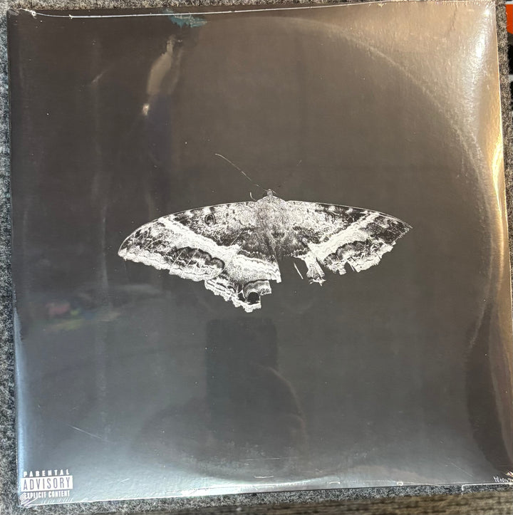 Kendrick Lamar – To Pimp A Butterfly record cover with a moth illustration on a reflective surface