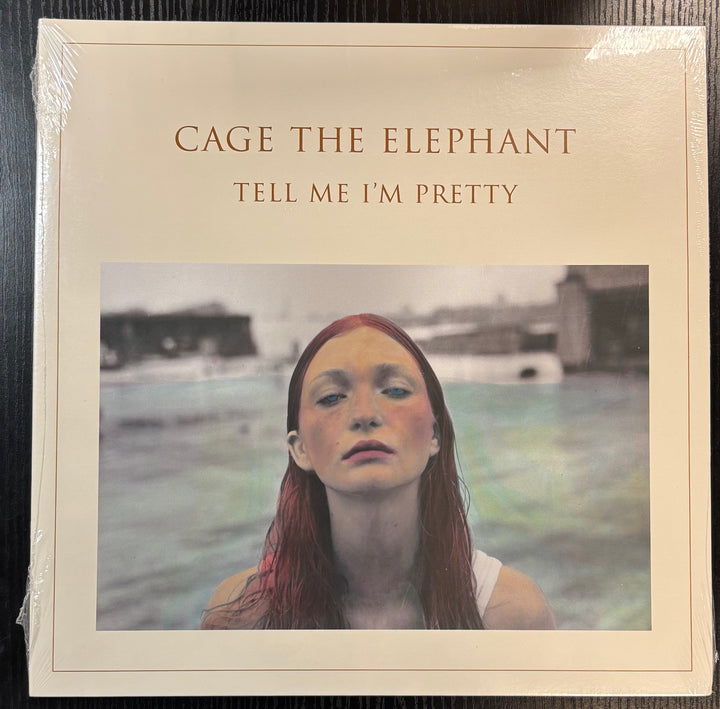 Album cover of 'Tell Me I'm Pretty' by Cage the Elephant with a person's face on a blurred background.