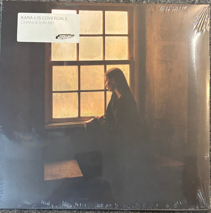 Kara-Lis Coverdale's album 'Changes in Air' vinyl record cover, sealed in plastic shrink wrap. The cover art features a woman in profile looking out a window with warm golden light, set against a dark, moody background.