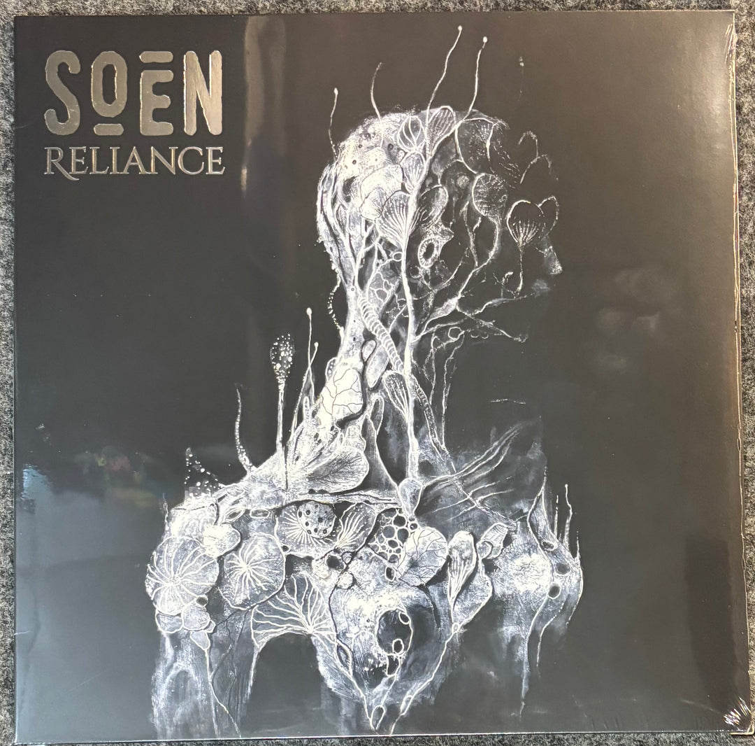 Album cover for 'Reliance' by SOEN with intricate white design on a dark background