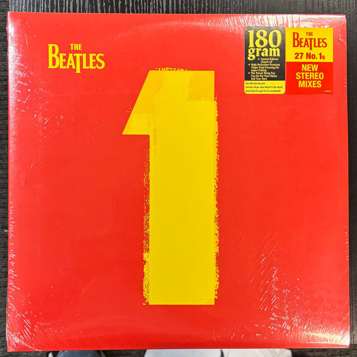 Beatles, The - 1 record cover with 'The Beatles' branding and a large yellow number '1' on a red background.