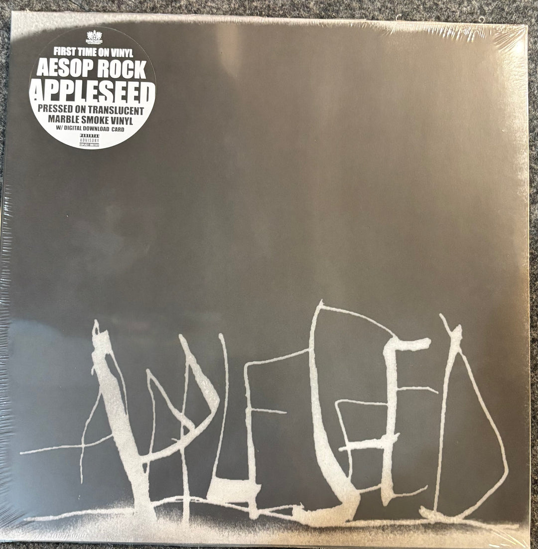 Aesop Rock 'Appleseed' vinyl record sleeve on translucent shrink wrap, photographed flat against a dark textured surface. The cover is black with a large white abstract logo and a white circular 'First Time on Vinyl' sticker at the top left.