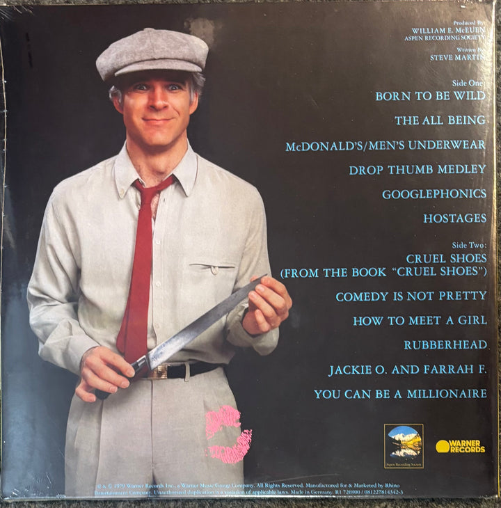 Vinyl record cover for Martin, Steve - Comedy Is Not Pretty, featuring a photo of Steve Martin holding a knife, with tracklist text on a dark background.