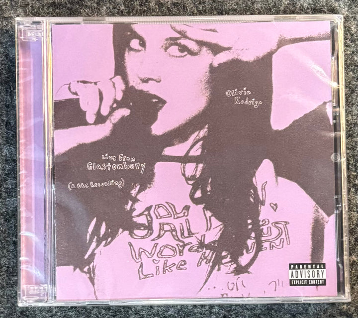 OLIVIA RODRIGO – LIVE FROM GLASTONBURY CD cover with a stylized portrait and text on a pink background