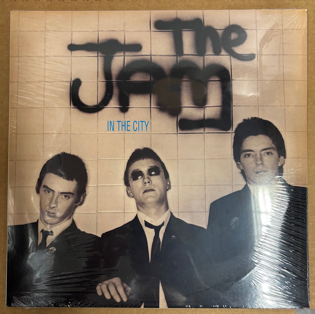 Album cover of 'The Jam In The City' with black and white photo of three band members.