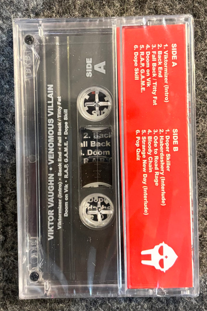 VIKTOR VAUGHN (MF DOOM) - VENOMOUS VILLAIN 2 Cassette tape with red and black label on a textured surface