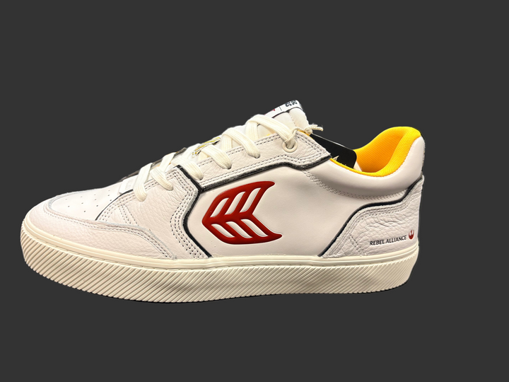 White sneaker with red logo on a dark surface, with blurred background