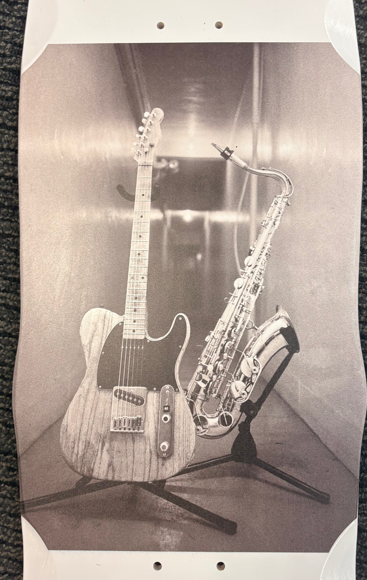 Skateboard with a guitar and saxophone photo on a textured surface