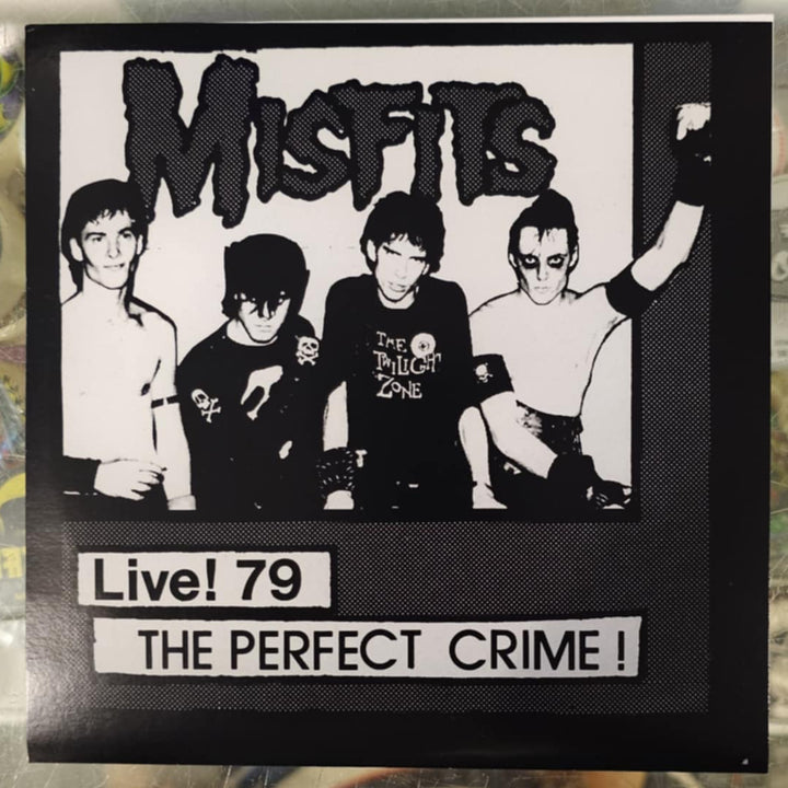 Framed poster of a band with text 'Misfits Live! 79 The Perfect Crime!' on a reflective surface.