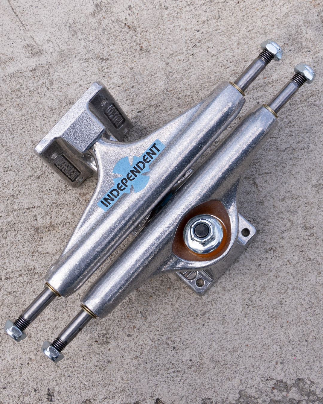 Independent Legacy OGBC Stage 11 trucks on concrete, showing the blue hanger logo and orange bushings.