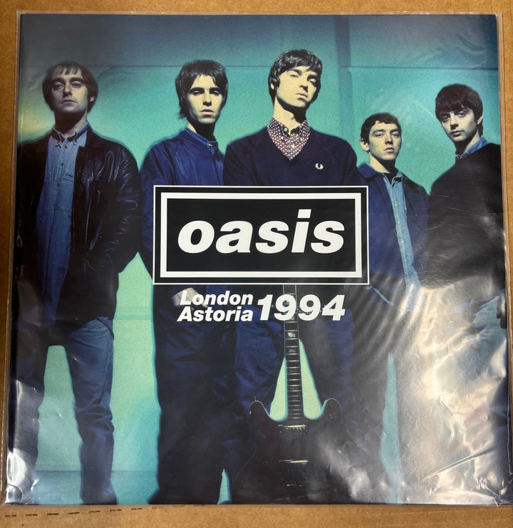 Album cover of Oasis with band members and 'Oasis London Astoria 1994' text.