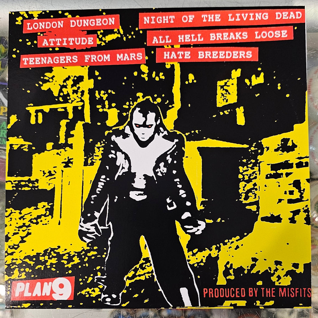 Vinyl record with a yellow and black cover featuring a person and text, placed on a reflective surface.