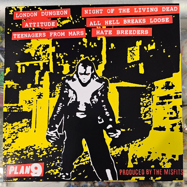 Vinyl record with a yellow and black cover featuring a person and text, placed on a reflective surface.